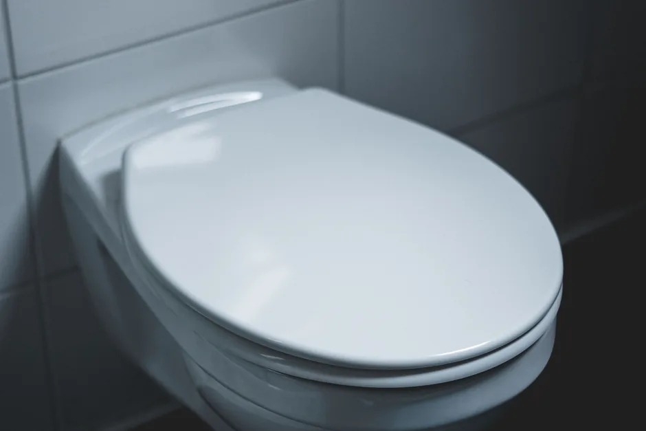 A white wall-hung toilet pan against grey tiles with no visible cistern