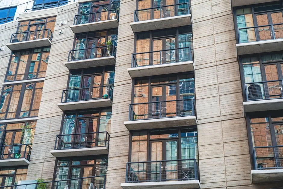 A modern apartment building with rows of balconies seen from street level