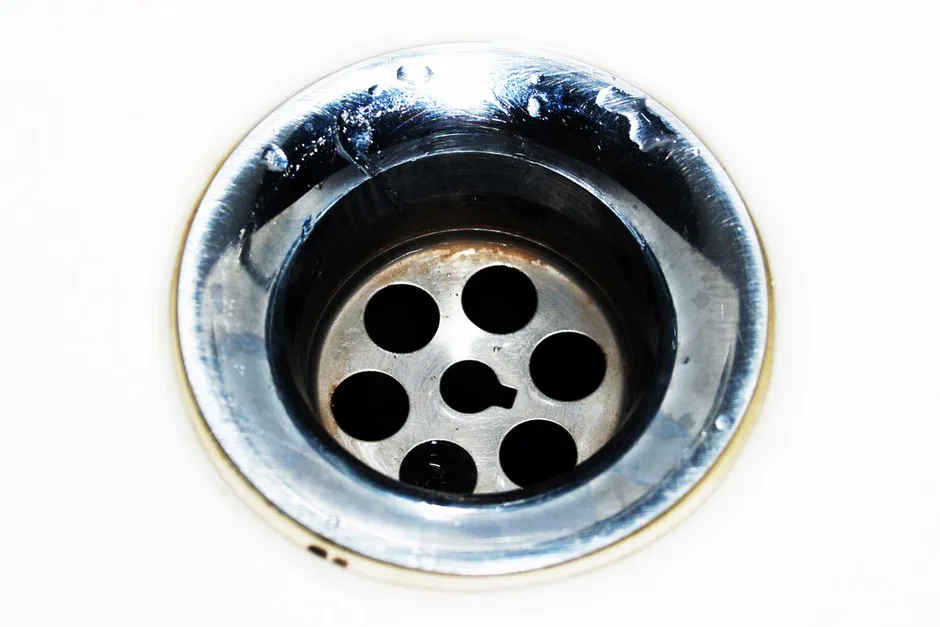 A chrome waste outlet coated in dark grease and grime