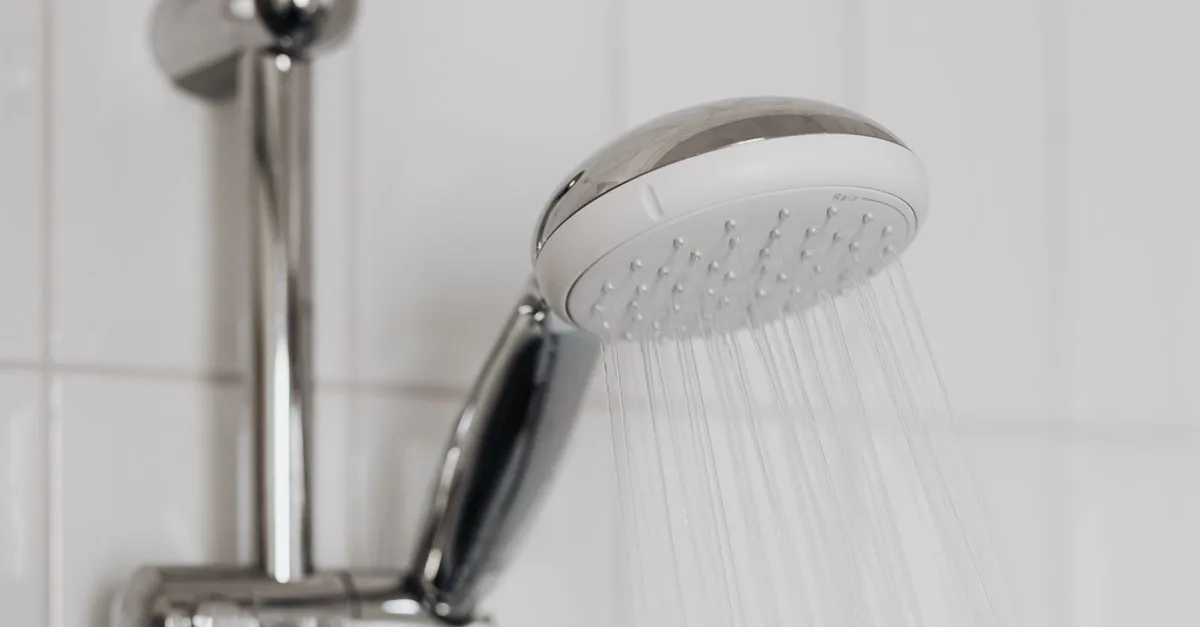 A chrome rail shower with water running from the rose