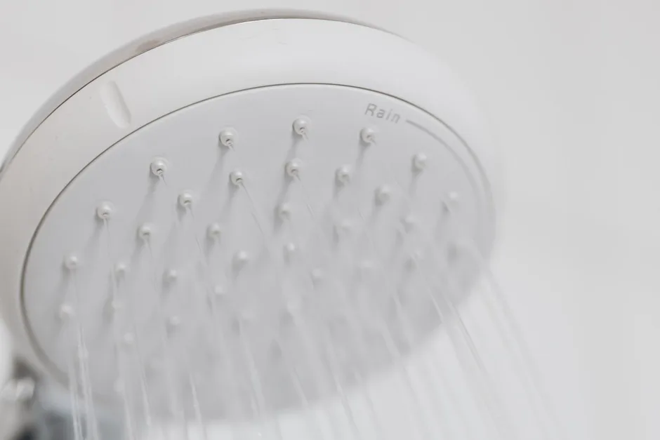 Close-up of a shower rose face with rubber nozzles and water running through them